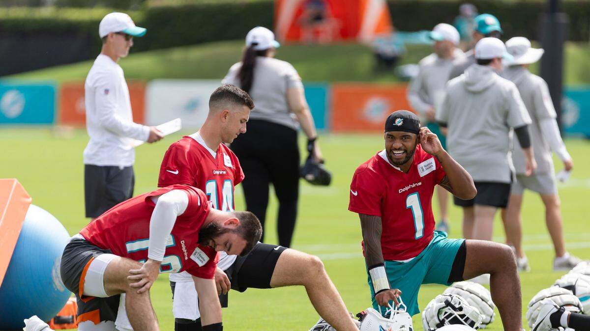 El quarterback de los Dolphins Tua Tagovailoa (1) conversa con Mike White (14) y Skylar Thompson durante una práctica del equipo en el Baptist Health Training Complex en Miami Gardens, Florida, el 5 de agosto de 2024.
