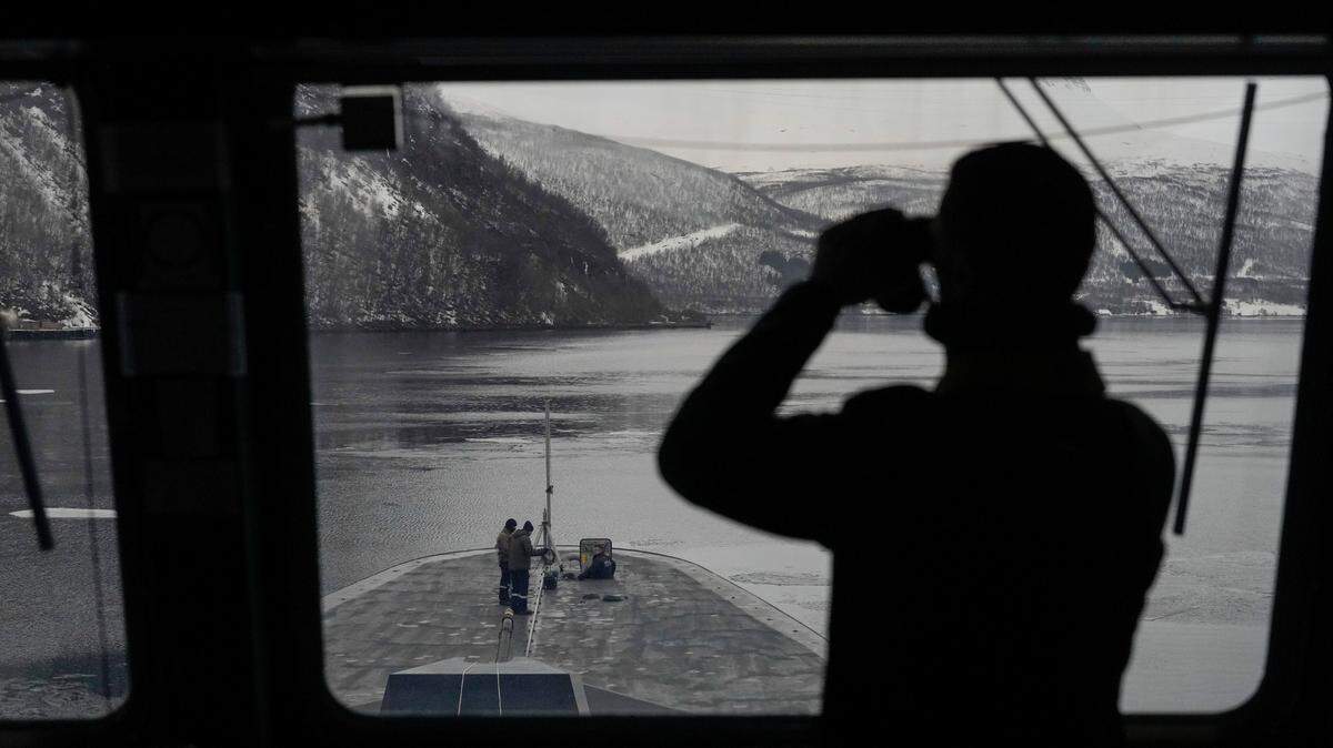Un marinero francés utiliza unos prismáticos para revisar la zona a bordo de la fragata francesa Normandie, durante una maniobra en un fiordo noruego al norte del círculo polar ártico, el 8 de marzo de 2024. 
