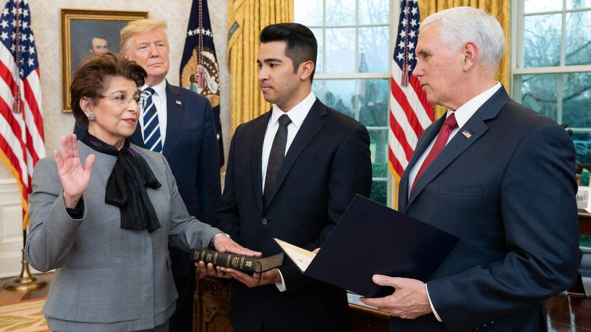 El presidente Donald Trump observa cómo el vicepresidente Mike Pence oficia la juramentación ceremonial de Jovita Carranza como titular de la Administración de Pequeñas Empresas, junto a su nieto Anthony Hernández, quien sostiene la biblia, este lunes 27 de enero de 2020, en el Despacho Oval de la Casa Blanca.