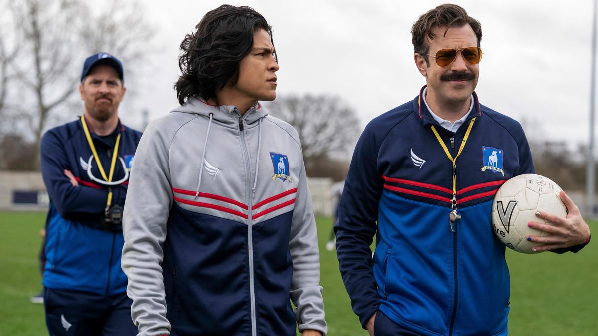 Esta imagen difundida por Apple TV + muestra a Brendan Hunt, de izquierda a derecha, Cristo Fernández y Jason Sudeikis en una escena de “Ted Lasso”. La segunda temporada se estrena el 23 de julio (Apple TV + vía AP).