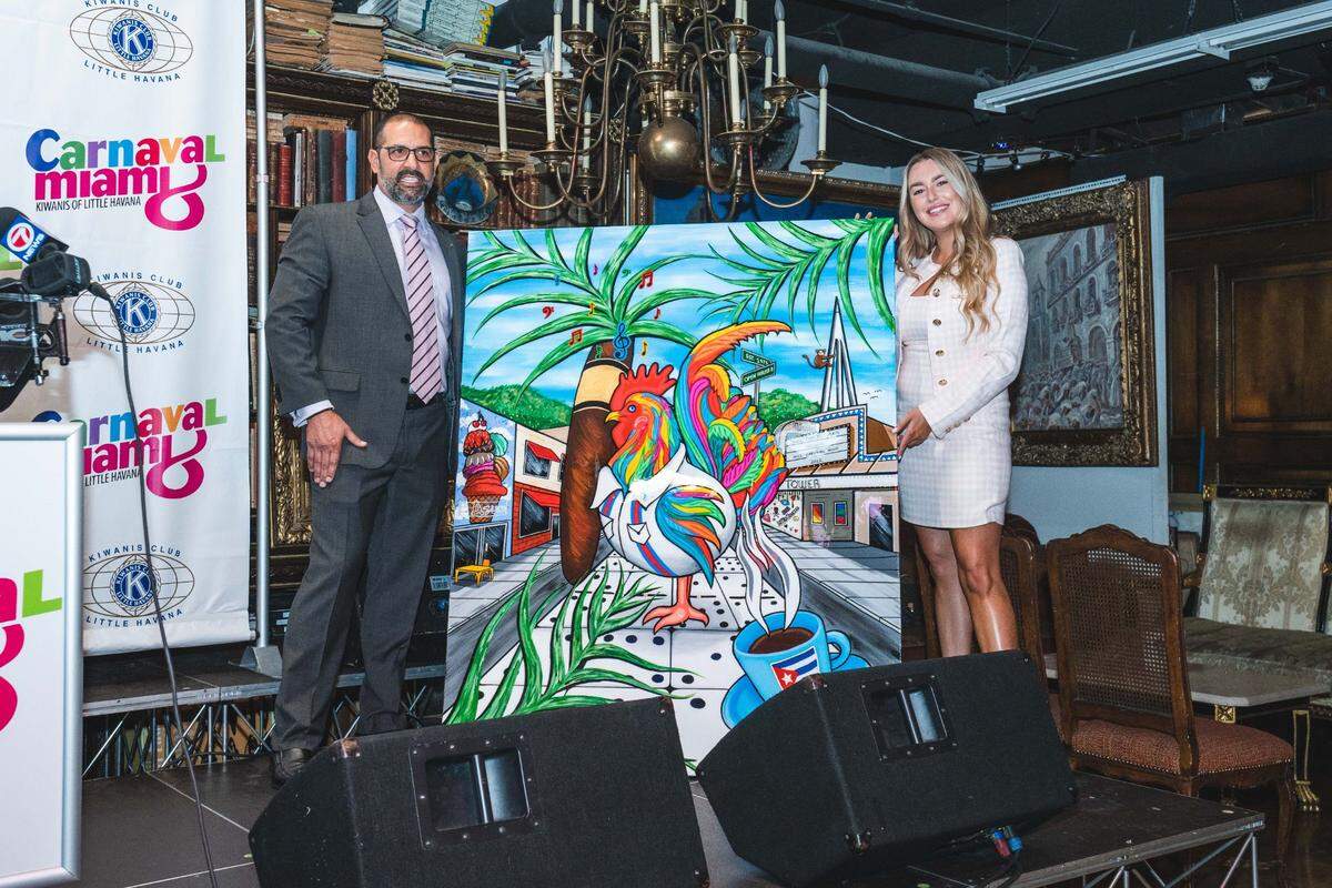 El presidente del Club Kiwanis de La Pequeña Habana posa con Laura Chirino, creadora del afiche del Carnaval Miami 2022.