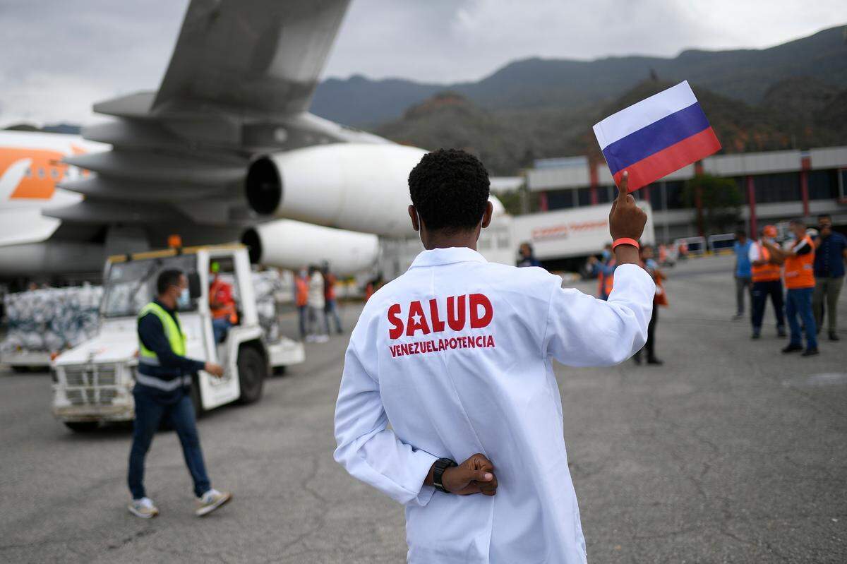 Foto de archivo. Un trabajador de la salud sostiene una bandera nacional rusa mientras es descargado un cargamento de la vacuna rusa Sputnik V contra el COVID-19, en el Aeropuerto Internacional Simón Bolí­var en Maiquetí­a, Venezuela, el 13 de febrero de 2021.