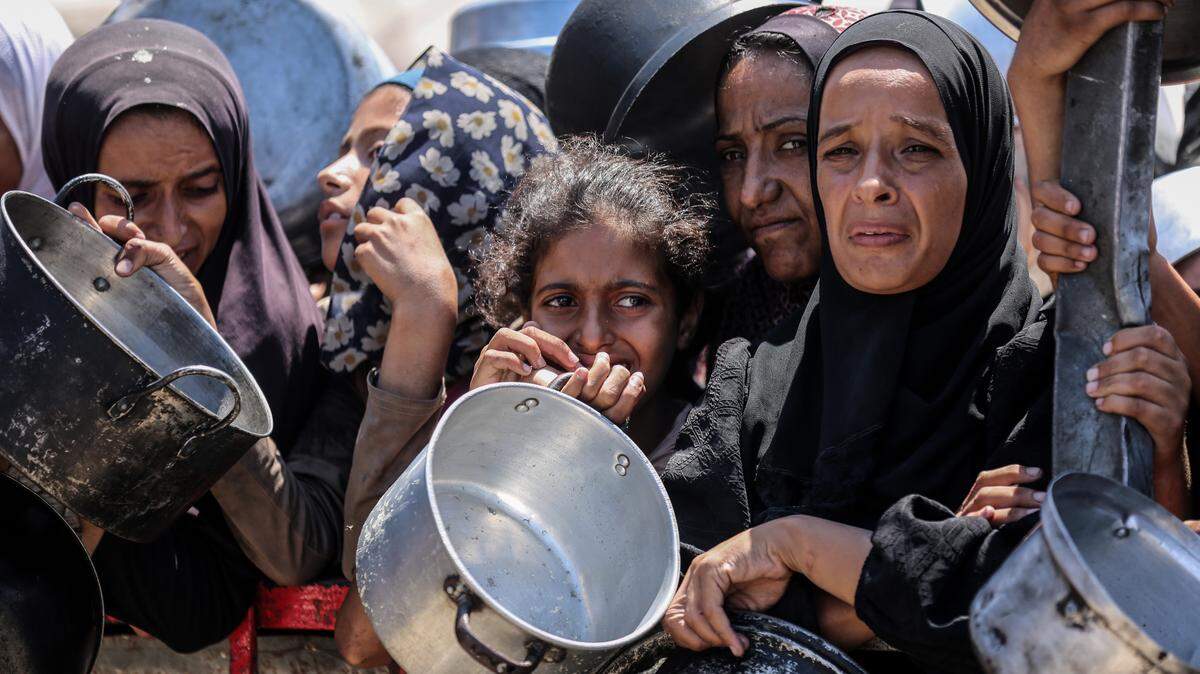 Decenas de palestinos hacen fila para recibir comida en un centro de distribución de alimentos, el lunes 4 de agosto de 2025, en Ciudad de Gaza.