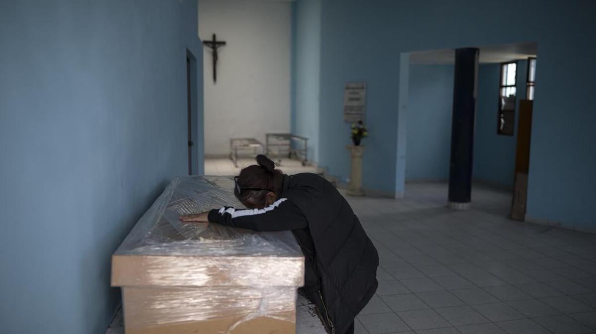Elizabeth Alvarado, de 53 años, llora sobre el ataúd de cartón que contiene el cadáver de su esposo Víctor Argüelles, quien murió por complicaciones del COVID-19, antes de su cremación en el cementerio El Ángel en Lima, Perú, el miércoles 23 de septiembre de 2020