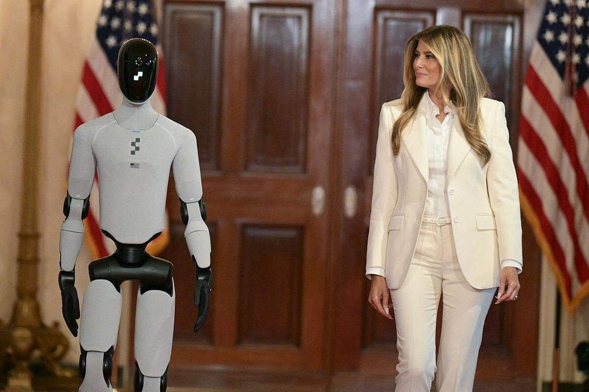 La primera dama de EEUU, Melania Trump, camina junto a un robot humanoide a su llegada a la Cumbre de la Coalición Global, “Fomentando el futuro juntos”, celebrada en el Salón Este de la Casa Blanca en Washington, D.C., el 25 de marzo de 2026.