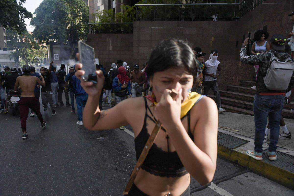 Una mujer huye de los gases lacrimógenos lanzados por agentes de la Guardia Nacional para reprimir una protesta en contra de los resultados de las elecciones presidenciales en Venezuela, el lunes 29 de julio de 2024, en el vecindario de Petare de Caracas.