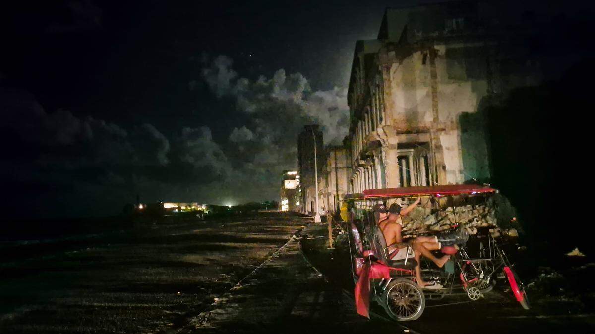 Durante un apagón en toda la isla, dos hombres se sientan en un bicitaxi el 20 de octubre de 2024, Cuba, La Habana.