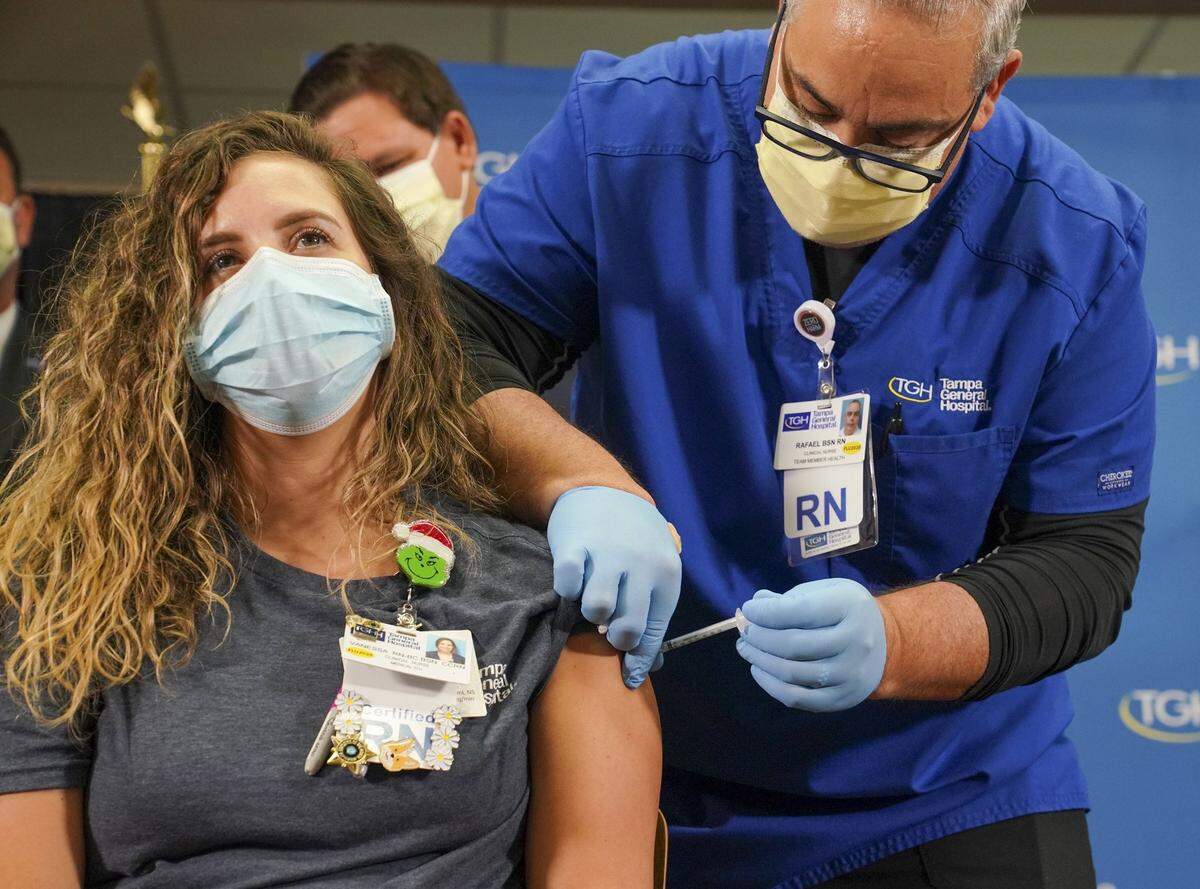 La enfermera Vanessa Arroyo recibe una vacuna contra el COVID-19 de parte del enfermero Rafael Martínez, el pasado 14 de diciembre de 2020 en el Hospital General de Tampa.