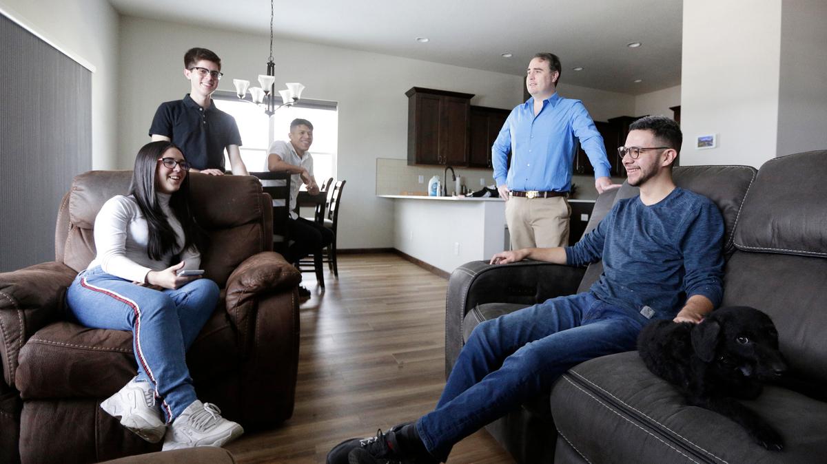 El doctor Kyle Varner ( segundo desde la derecha), quien patrocina y ofrece vivienda a venezolanos que llegan a Estados Unidos a través del parole humanitario, habla en su casa con un grupo de beneficiarios el 6 d enero de 2023.