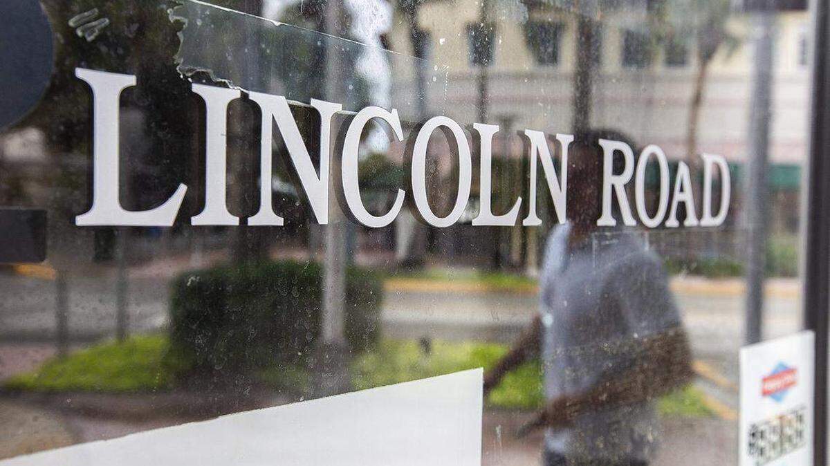 Un hombre que camina por Lincoln Road Mall de Miami Beach se refleja en el escaparate de una tienda vacía.