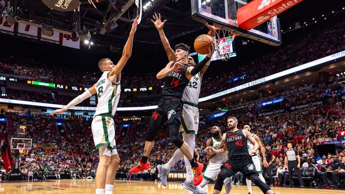 El jugador del Heat Tyler Herro (14) trata de pasar la pelota ante la marca de Kristaps Porzingis (8) y Al Horford (42), de los Celtics de Boston, en el partido celebrado el 11 de febrero de 2024 en Miami.