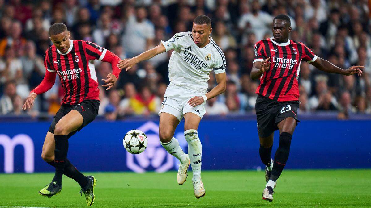 El delantero del Real Madrid Kylian Mbappé (centro) conduce la pelota ante la defensa del AC Milan, en el partido de la Liga de Campeones celebrado el 5 de noviembre de 2024 en el estadio Santiago Bernabéu en Madrid.