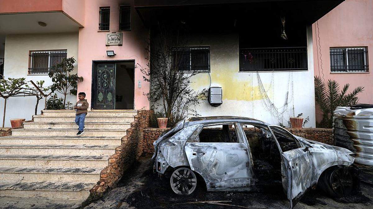 Un niño palestino permanece de pie junto a un automóvil destruido y una vivienda calcinada tras un presunto ataque perpetrado por colonos israelíes en la aldea de Deir al-Hatab, al este de la ciudad de Nablus, en la Cisjordania ocupada por Israel, el lunes 23 de marzo de 2026.