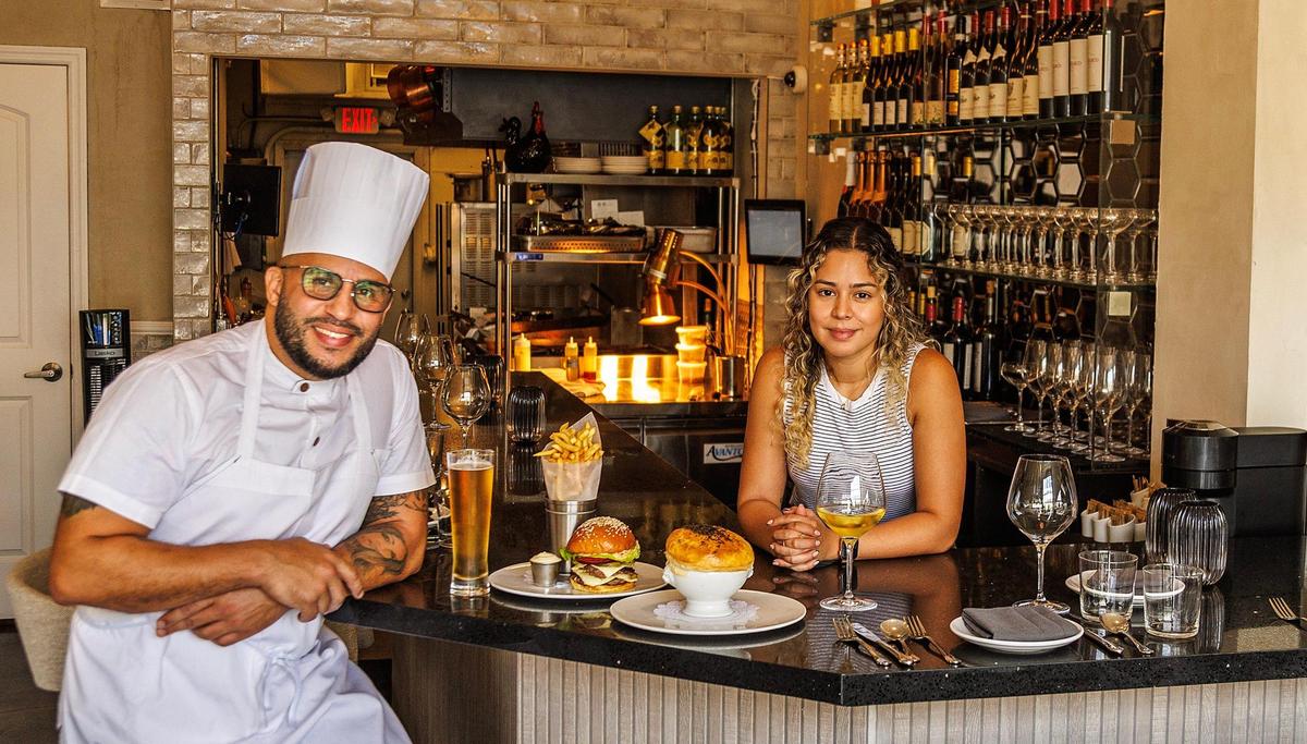 El chef y propietario Nuno Grullón y su esposa y copropietaria Crystal Péez muestran una hamburguesa Grand Central con papas fritas y pastel de pollo con trufa en el restaurante del mismo nombre, Grand Central.