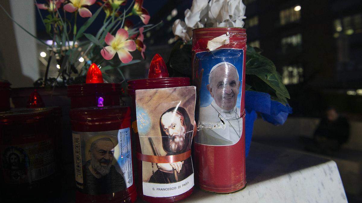  Una vela con una imagen del Papa Francisco está colocada en la base de una estatua del Papa Juan Pablo II en el hospital Gemelli, donde el Papa Francisco está hospitalizado para pruebas y tratamiento de bronquitis en Roma. 