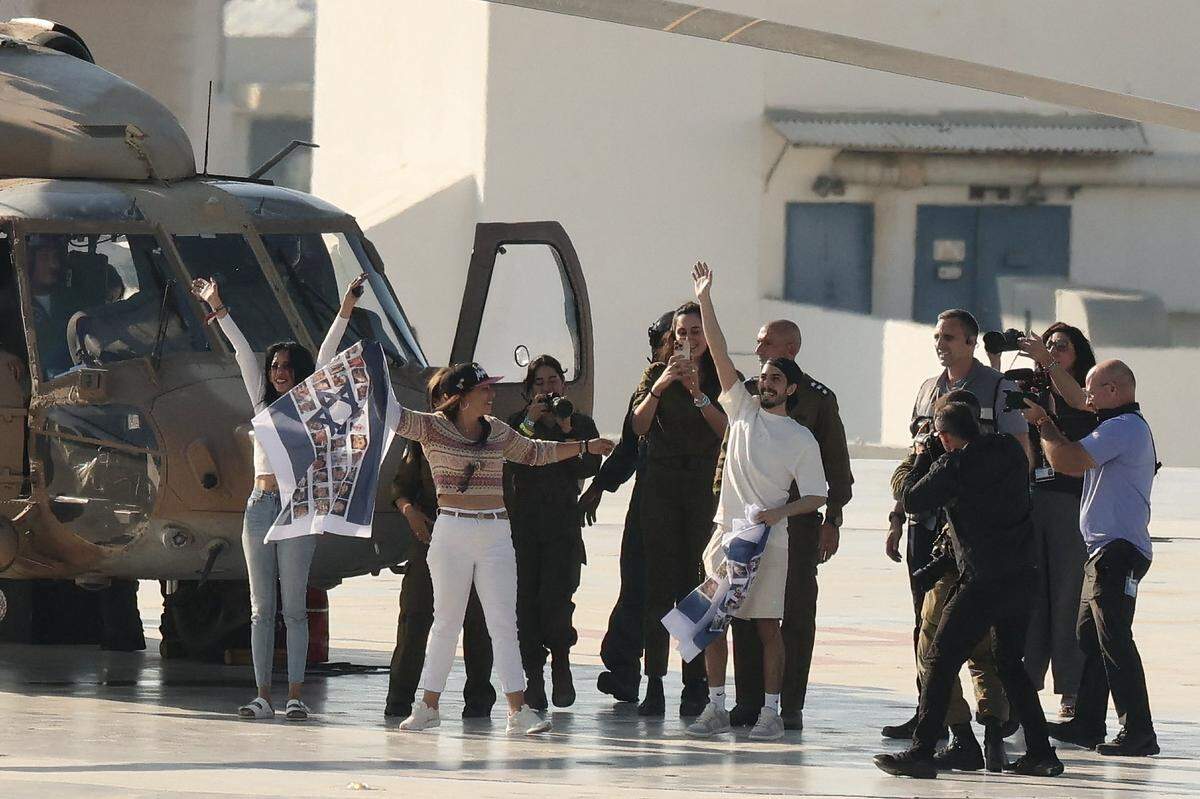 Former Israeli hostage Matan Zangauker (C-R), who was held captive in Gaza since the 2023 October 7 attacks by Palestinian militants, waves as he stands next to his girlfriend and former hostage Ilana Gritsevsky (2nd from L) and his mother Einav Zangauker (L) upon disembarking from an Israeli military helicopter on the landing pad at Ichilov Sourasky Medical Centre in Tel Aviv on October 13, 2025. Twenty living Israeli hostages were released on October 13 after more than two years in captivity in Gaza, as part of a ceasefire deal with Hamas. Militants kidnapped them during Hamas's October 7, 2023 attack on Israel, the deadliest in the country's history. (Photo by Jack GUEZ / AFP) (Photo by JACK GUEZ/AFP via Getty Images)