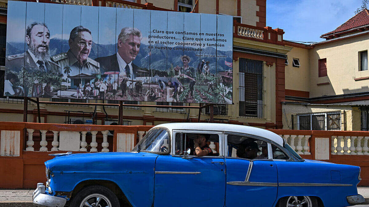 Un viejo coche estadounidense pasa junto a un cartel en el que aparecen el difunto líder cubano Fidel Castro (izquierda), el expresidente Raúl Castro (centro) y el actual gobernante de Cuba, Miguel Díaz-Canel (derecha), en La Habana, el 19 de junio de 2026.