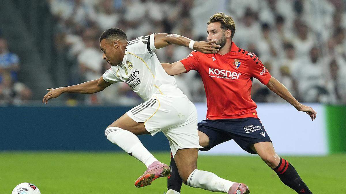 El delantero del Real Madrid Kylian Mbappé (izq.) trata de superar la marca de Jon Moncayola, de Osasuna, en el partido de la liga española celebrado el 19 de agosto de 2025 en el Estadio Santiago Bernabéu de Madrid.