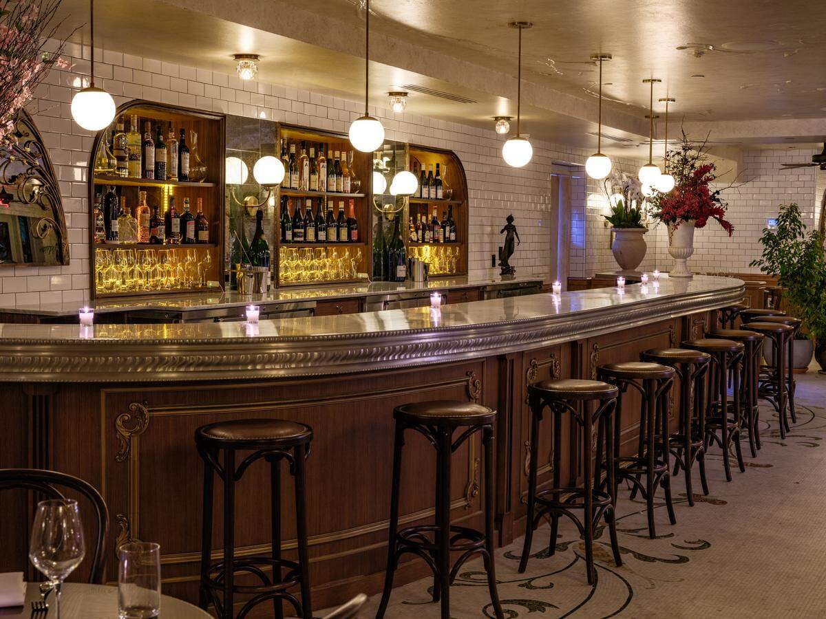 Bar de estilo clásico con detalles en latón y superficies de mármol.