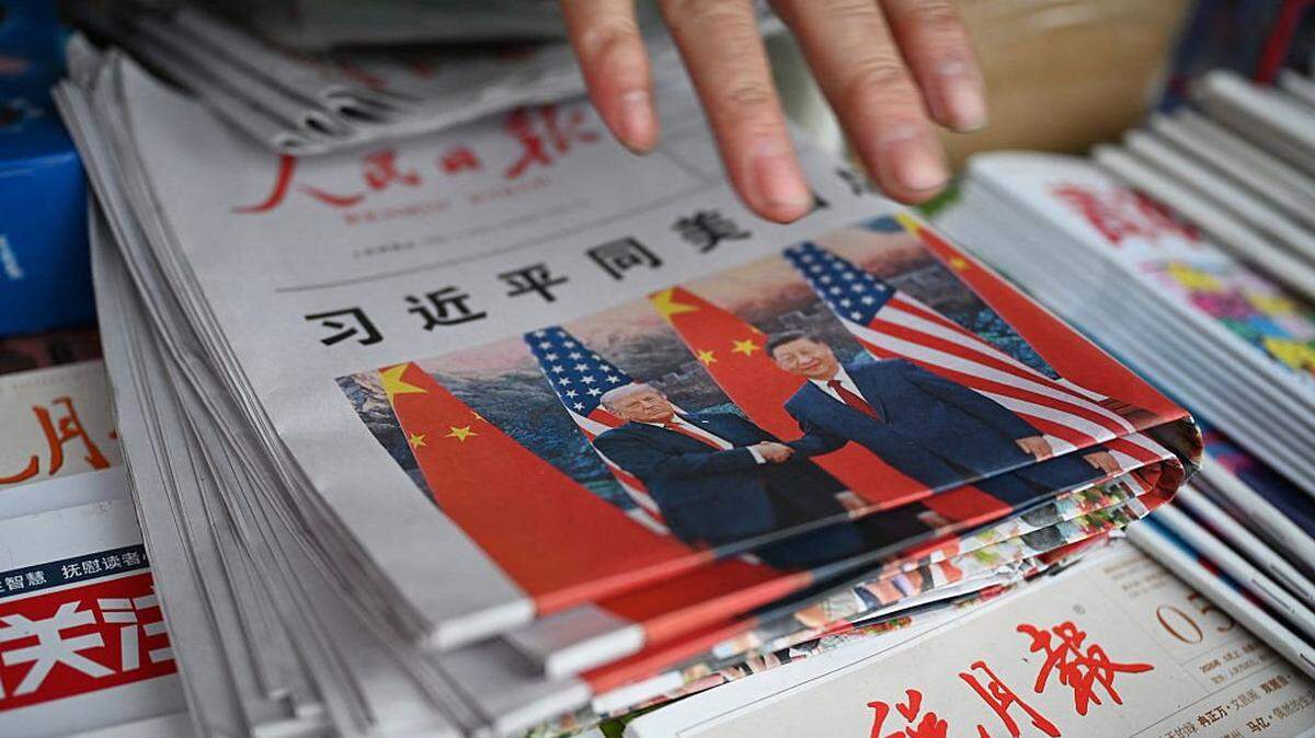 Ejemplares del periódico *People’s Daily*, con una fotografía en portada y un titular que reza “Xi Jinping mantiene conversaciones con el presidente estadounidense Donald Trump”, se exhiben en un quiosco de Pekín el 15 de mayo de 2026. Trump afirmó haber cerrado “fantásticos acuerdos comerciales” con el líder chino Xi Jinping, durante el encuentro que ambos mantuvieron el 15 de mayo en el marco de las conversaciones finales de una cumbre de superpotencias que, según el líder estadounidense, ha propiciado también una oferta por parte de China para ayudar a abrir el estrecho de Ormuz.