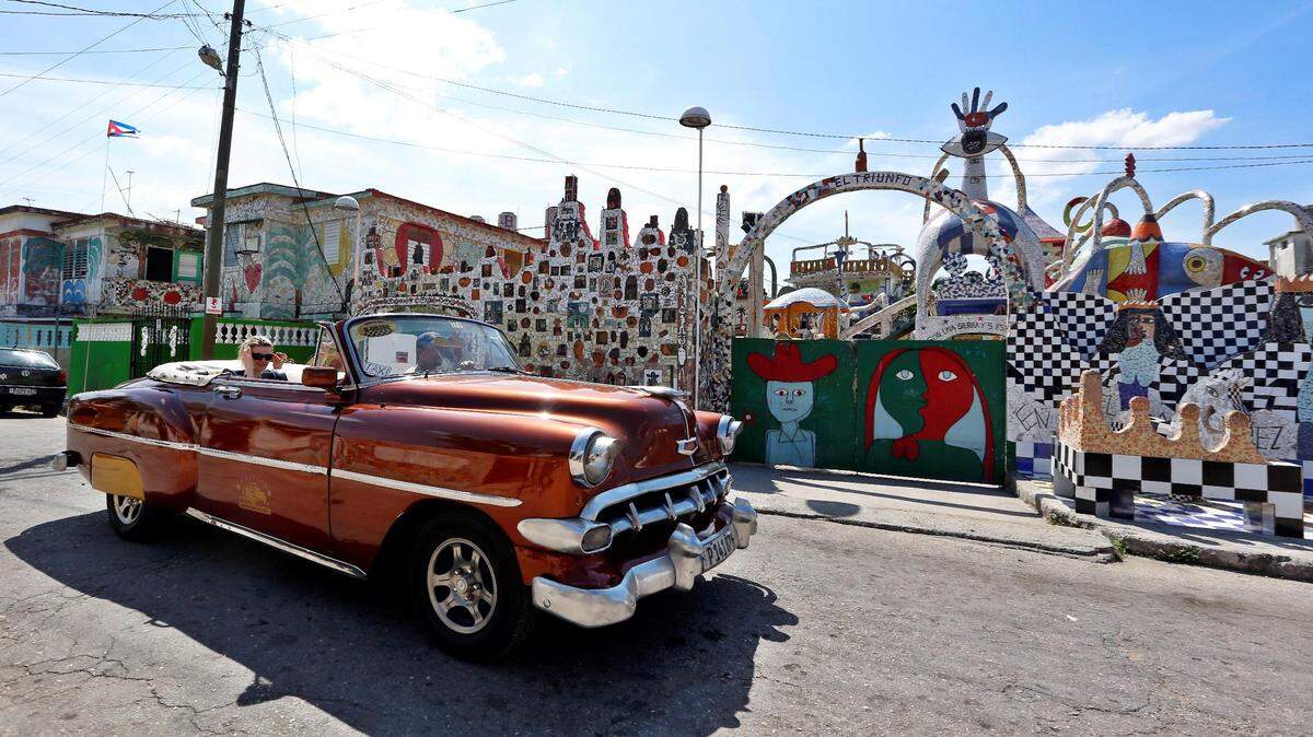 Un auto clásico con turistas pasa frente al estudio y taller del artista cubano José Antonio Rodríguez Fúster este miércoles 13 de marzo del 2019, en La Habana (Cuba).