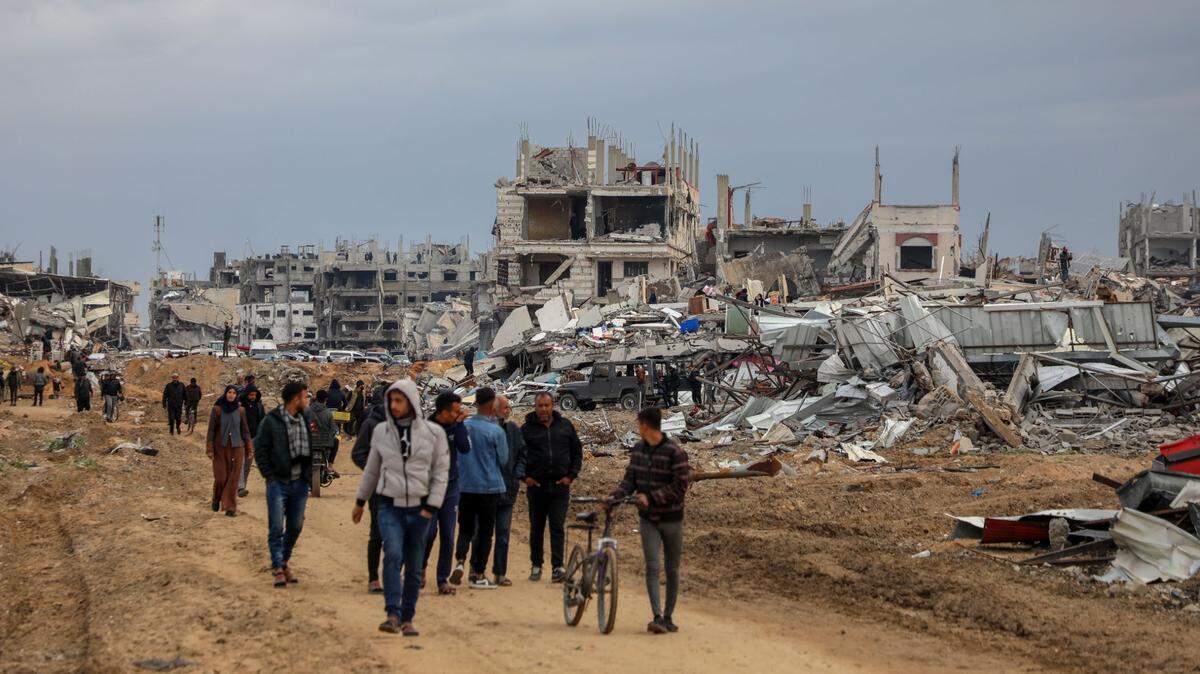Grupos de palestinos desplazados caminan cerca de un sector destruido por los bombardeos israelíes en la región central de la Franja de Gaza, el domingo 9 de febrero de 2025.