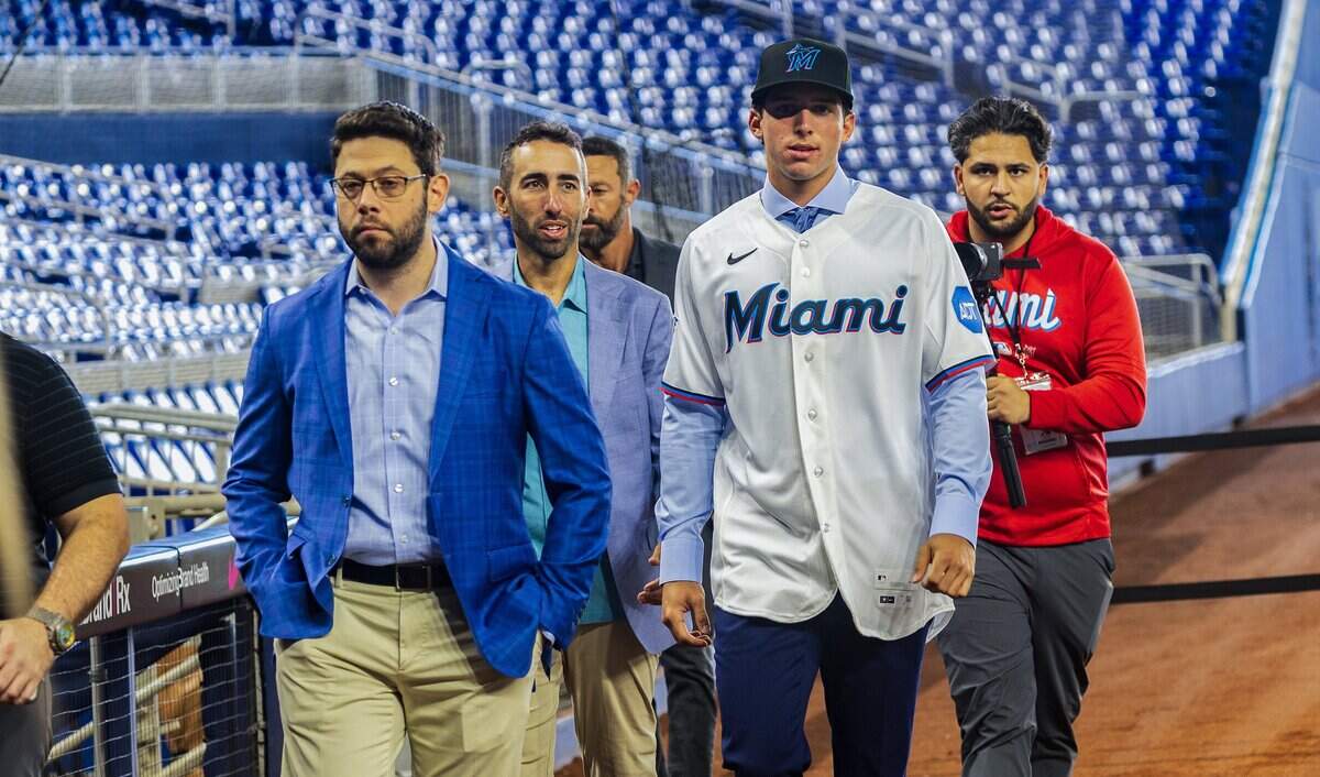 De izquierda a derecha, Peter Bendix, presidente de operaciones de béisbol de los Marlins, y Frankie Piliere, vicepresidente de iniciativas de proyecciones amateur y evaluación de jugadores, caminan junto a Jacob Lombard en su presentación oficial como nuevo jugador de la organización de los Marlins, el 16 de julio de 2026 en el loanDepot park, en Miami.