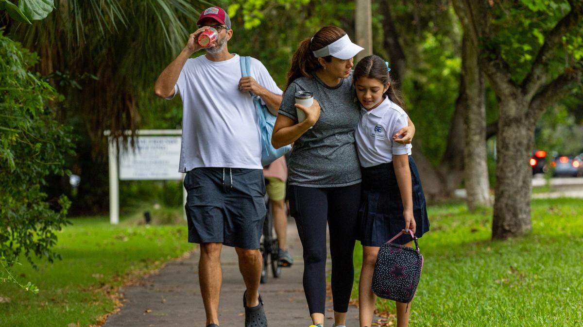Una familia camina hacia una escuela primaria para el primer día de clases en Miami, Florida, el jueves 17 de agosto de 2023.