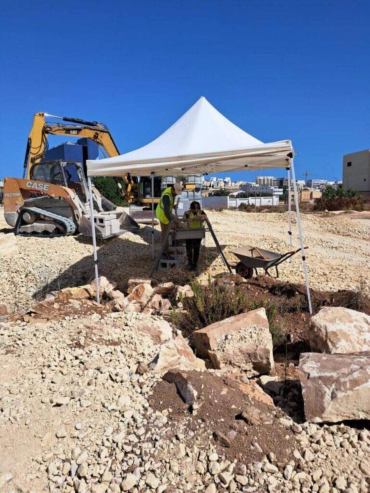 Las excavaciones de la tumba de 2,300 años con equipos de construcción al fondo.