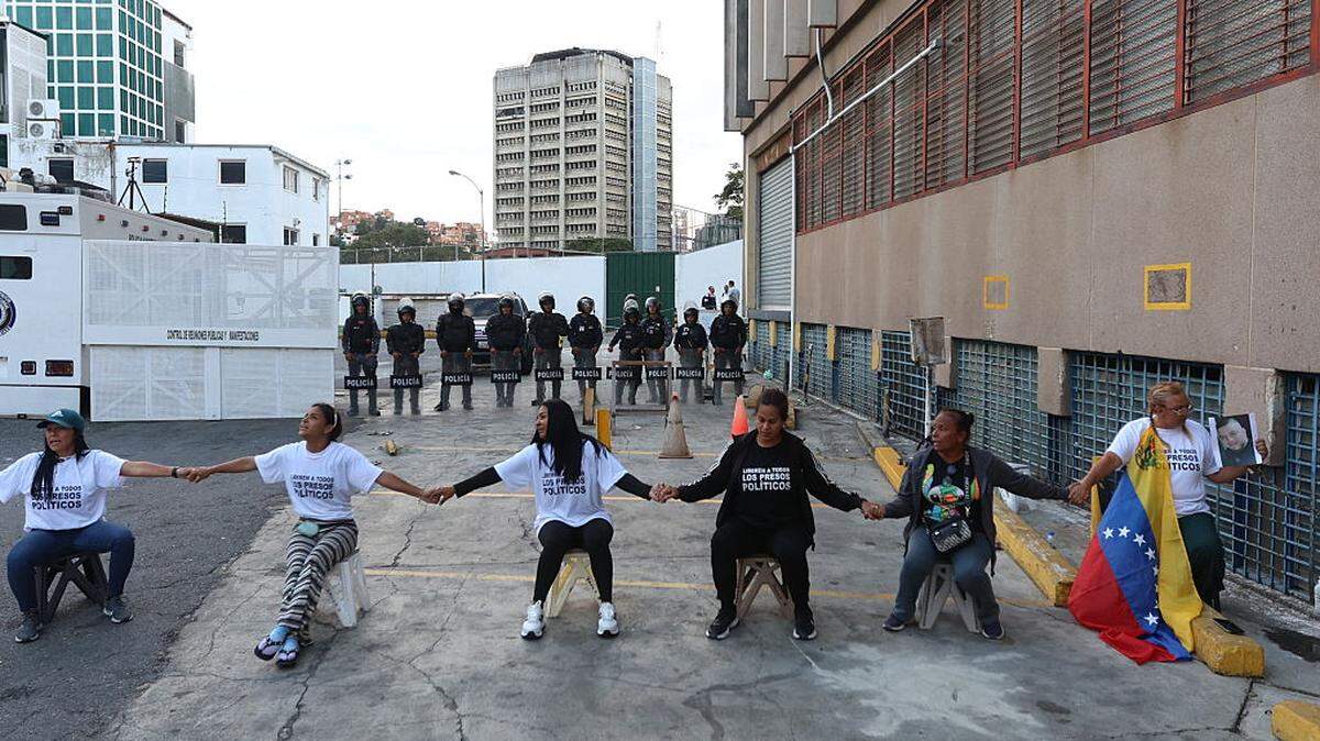 Women hold hands while waiting for news about the release of prisoners outside Zone 7 of the Bolivarian National Police in the Sucre municipality of the Metropolitan District of Caracas on Jan. 26, 2026. 