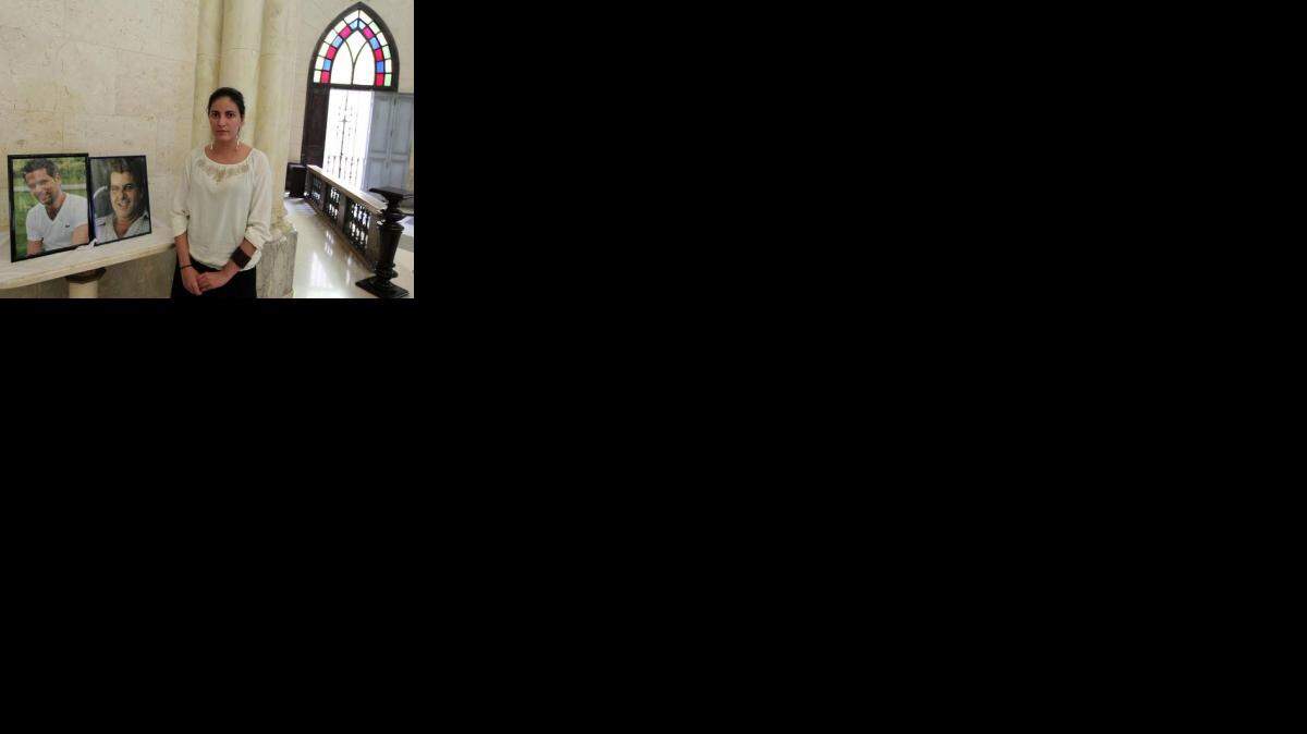 Rosa María Payá posa al lado de los retratos de su padre y Harold Cepero, en la Parroquia El Salvador del Mundo. (TWITTER)
