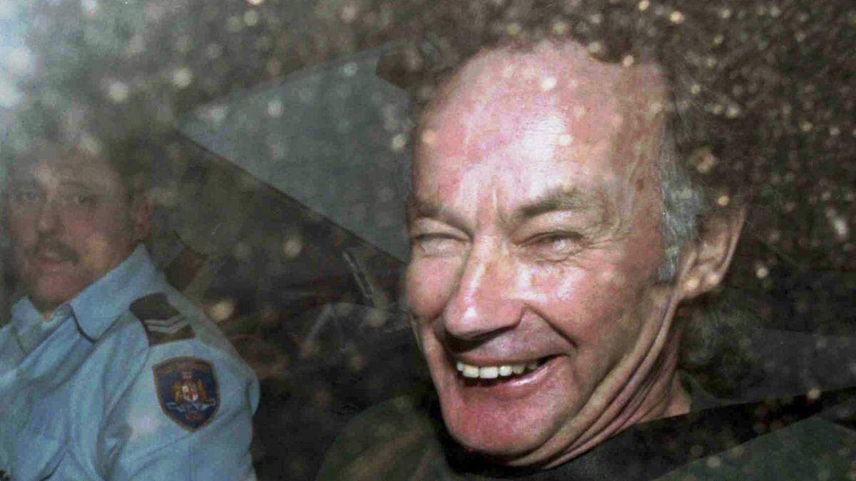 FILE - In this Nov. 4, 1997, file photo, Ivan Milat smiles in a police car after attending a court in Sydney, Australia. Milat, whose grisly serial killings of young backpackers horrified Australians in the early ’90s, died in a Sydney prison on Sunday, Oct. 27, 2019, prison authorities said. He was 74. (AP Photo/Rick Rycroft, File)