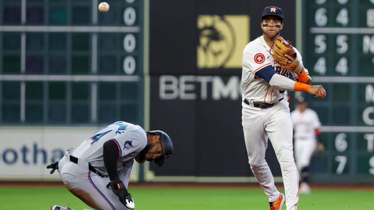 El campocorto de los Astros de Houston, Jeremy Peña (3), fuerza al jardinero izquierdo de los Marlins de Miami, Bryan De La Cruz (14), a salir en primera base en la primera entrada en Minute Maid Park.