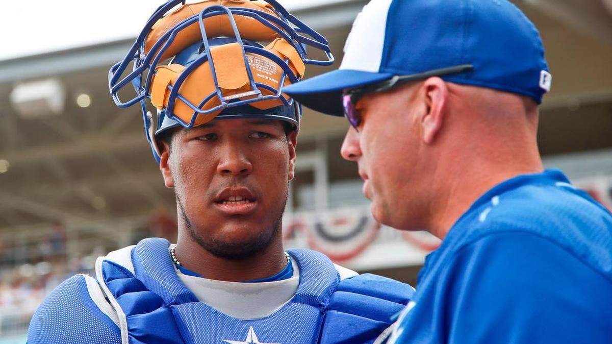 El receptor de los Reales de Kansas City, Salvador Pérez, escucha al entrenador del banco, Pedro Grifol, entre entradas de un partido de béisbol de entrenamiento de primavera contra los Padres de San Diego, el miércoles 11 de marzo de 2015, en Surprise, Arizona.