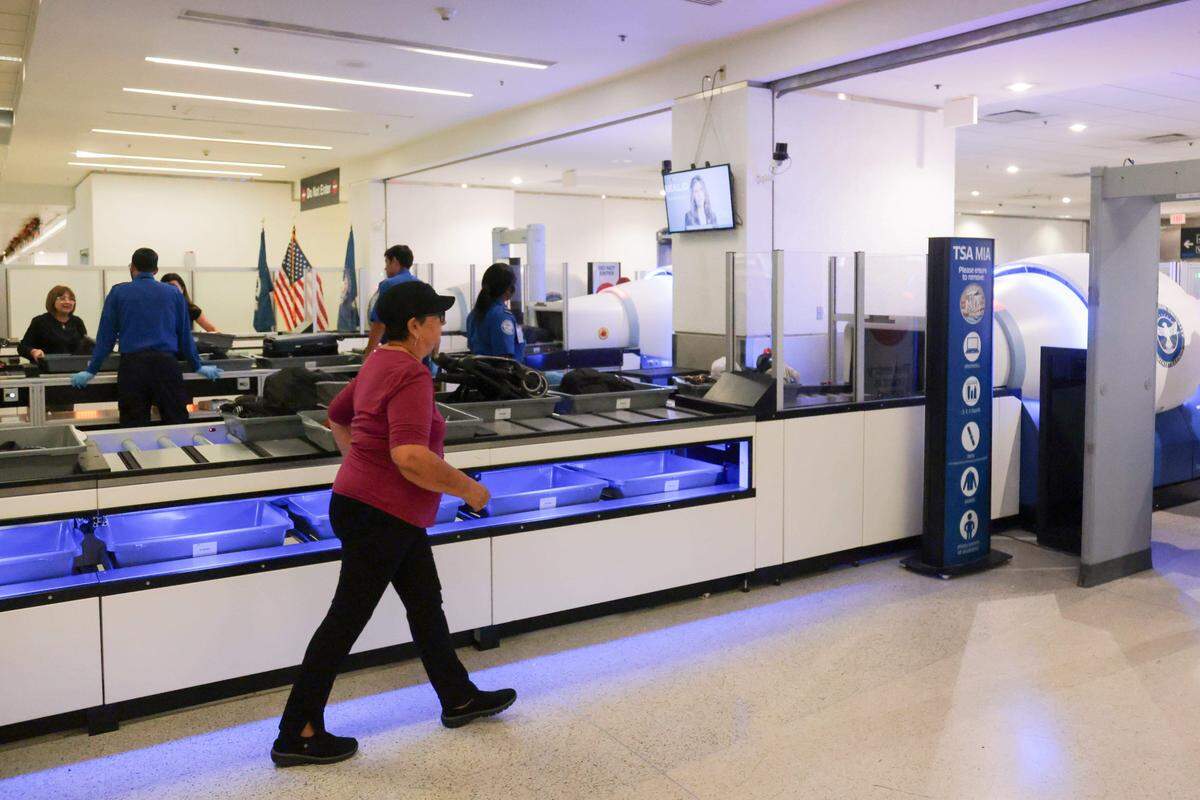 Una viajera se dirige a un detector de metales después de colocar su equipaje y pertenencias personales dentro del sistema automatizado de devolución de cestas en el puesto de control 2 del Aeropuerto Internacional de Miami.