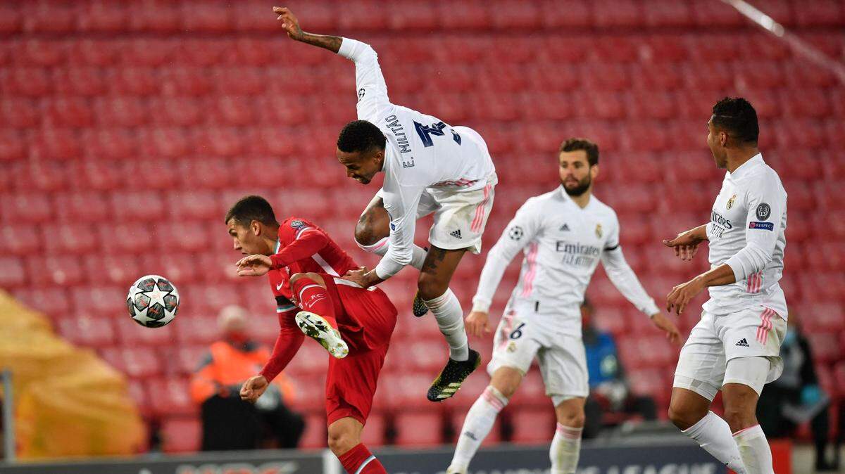 El jugador de Liverpool Roberto Firmino (izq.) lucha por la pelota con Eder Militao, del Real Madrid, en el partido de vuelta de cuartos de final de la Liga de Campeones, celebrado el 14 de abril de 2021 en Liverpool, Inglaterra.