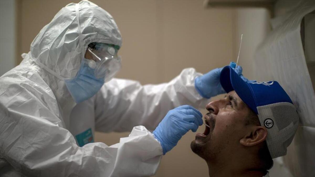 ARCHIVO: En esta foto de archivo del martes 14 de julio de 2020, un trabajador de salud toma una muestra para una prueba de PCR para el COVID-19 en un hospital local en Hospitalet, en las afueras de Barcelona, España.