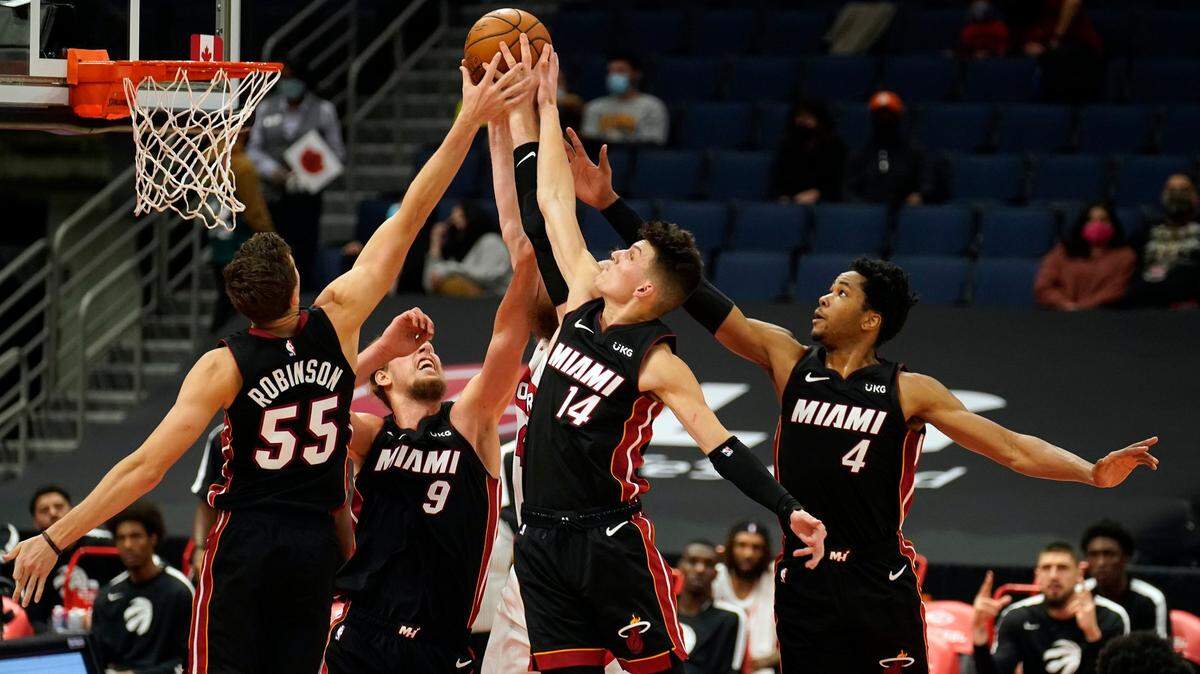 Duncan Robinson (55), Kelly Olynyk (9), el Tyler Herro y KZ Okpala (4), del Heat, buscan un rebote contra los Raptors este 18 de diciembre de 2020, en Tampa, Florida.