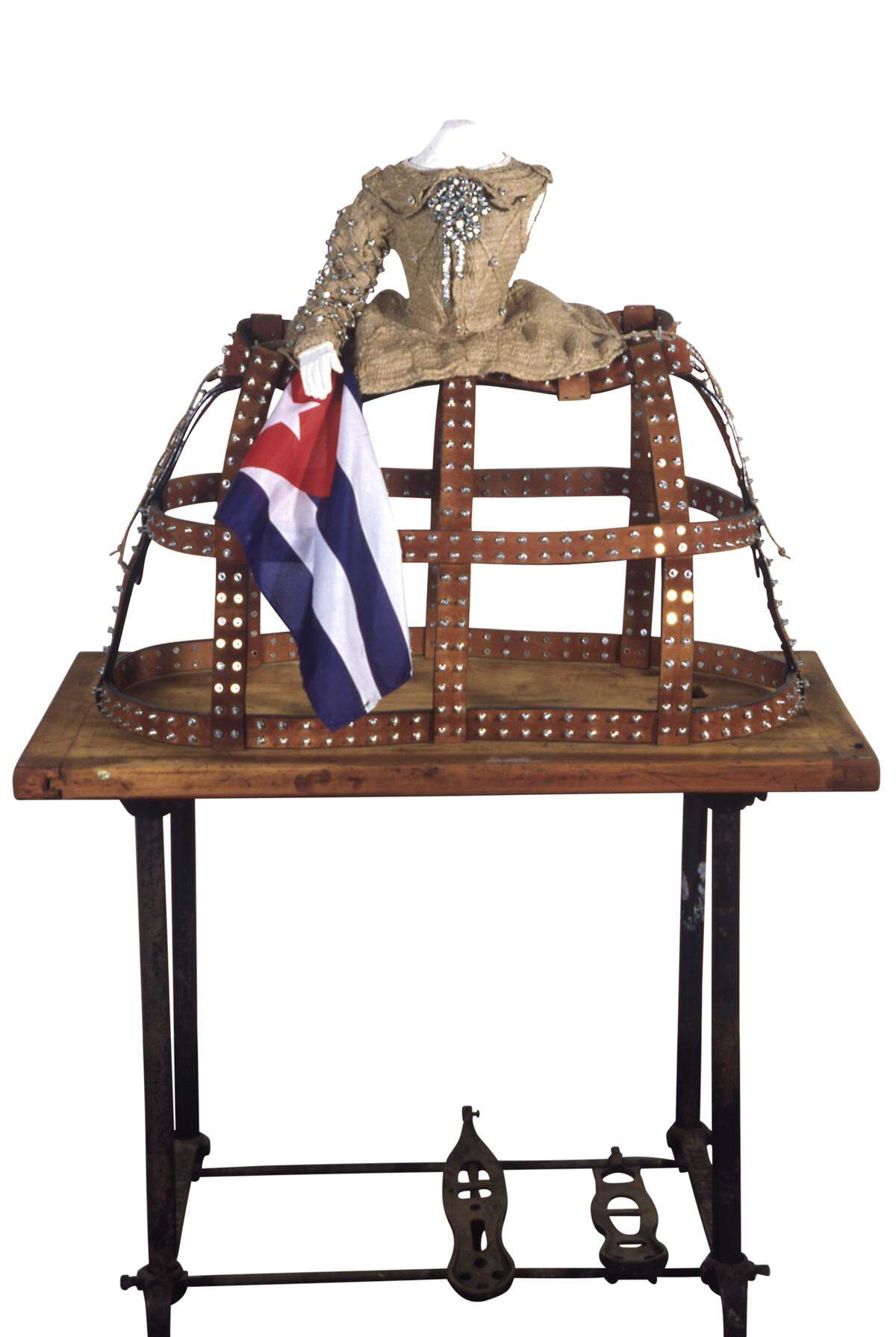 “La Habana para una Infanta difunta V”, 2002. Tejido artístico y tuercas metálicas sobre papel maché (torso) sobre cuero con tuercas y tornillos (crinolina de jaula). 50 x 81 x 40 pulgadas. Presentado en una mesa de máquina de coser antigua. Colección del artista: Nueva York.