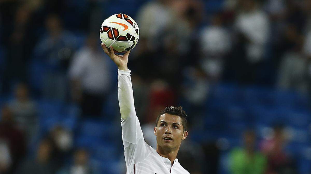 Cristiano Ronaldo sostiene una pelota por el Real Madrid en un partido contra el Elche en la liga española, el 23 de septiembre de 2014.