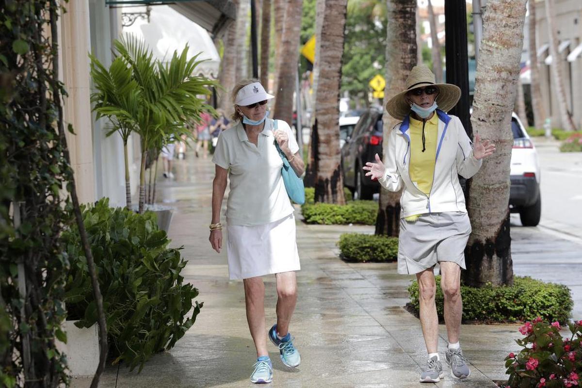 Robin Pickett and Peggy Mejia, wearing protective masks, walk along Worth Avenue in Palm Beach. Gov. Ron DeSantis said Tuesday that despite higher numbers of coronavirus cases, he won’t shut down the economy again.