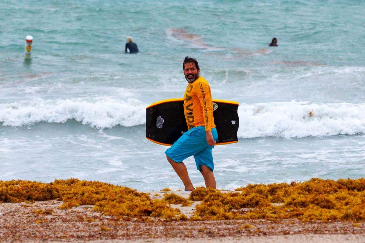 Un amante del surf camina por Bal Harbour Lighthouse el 12 de abril de 2023.  Se pronostican que regresen los fuertes oleajes al sur de la Florida, desde el martes 26 hasta el jueves 26 de octubere, según el NWS.