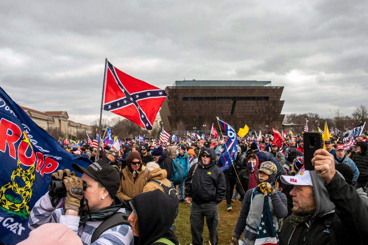 Un hombre enarbola la bandera confederada, con el Museo Nacional de Historia y Cultura Afroestadounidense de fondo, mientras el presidente Donald Trump se dirige a la multitud en Washington, el 6 de enero de 2021.