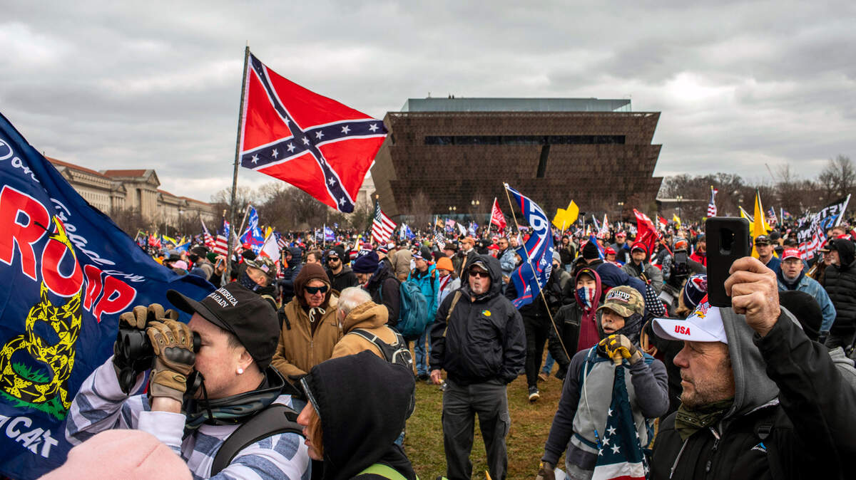 Un hombre enarbola la bandera confederada, con el Museo Nacional de Historia y Cultura Afroestadounidense de fondo, mientras el presidente Donald Trump se dirige a la multitud en Washington, el 6 de enero de 2021.