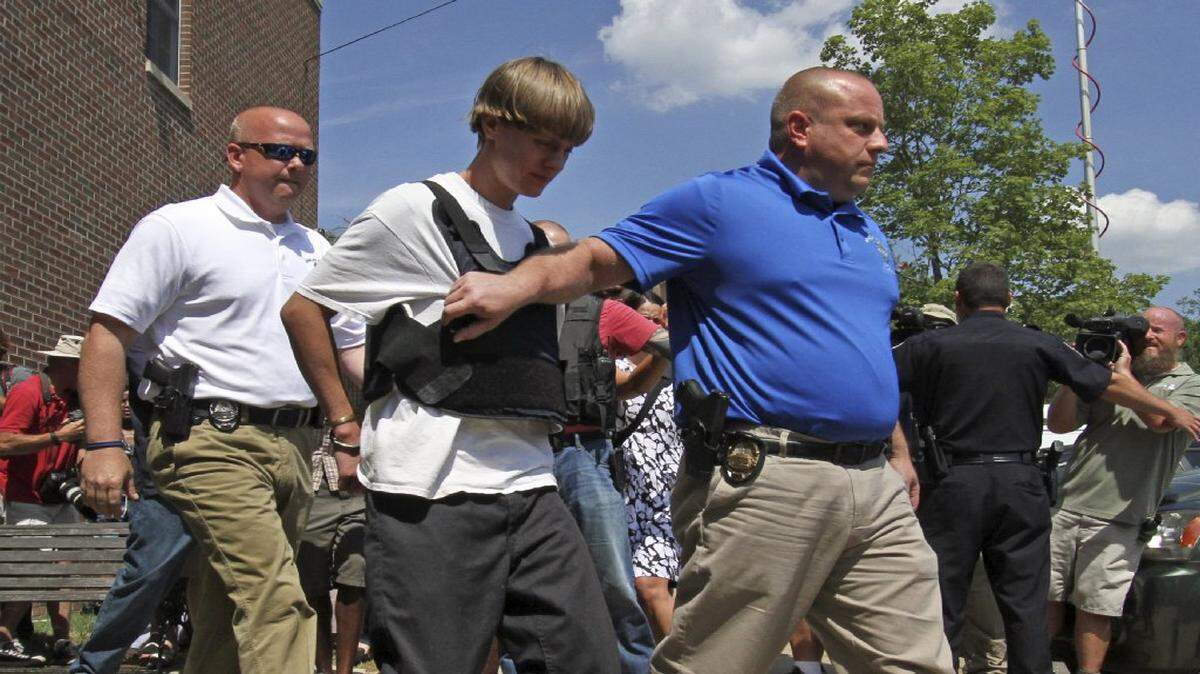 Dylann Storm Roof es escoltado desde el Departamento de Policía de Sheby en Shelby, Carolina del Norte, el jueves, 18 de junio de 2015. Roof es un sospechoso en el asesinato de varias personas la noche del miércoles en una histórica iglesia de la comunidad negra en el centro de Charleston.