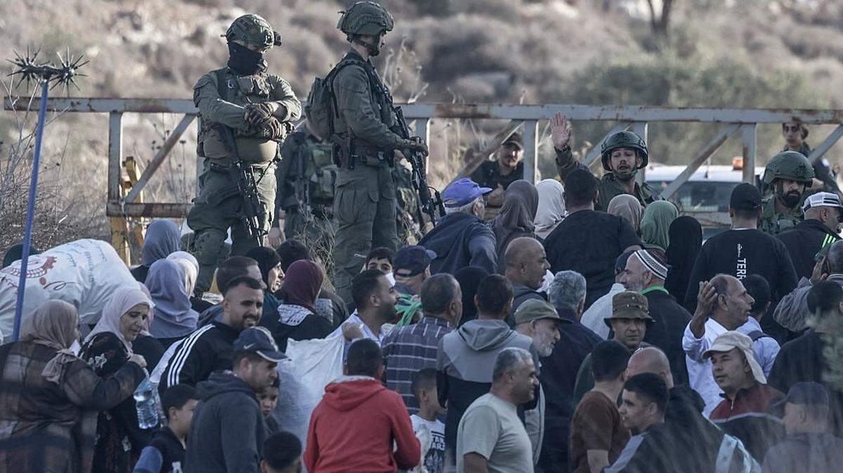 TOPSHOT - Israeli soldiers stop Palestinian farmers from Salem village at a checkpoint before entering through a closed gate onto their land to pick olives, east of Nablus in the occupied West Bank, on November 22, 2025. (Photo by Jaafar ASHTIYEH / AFP via Getty Images)