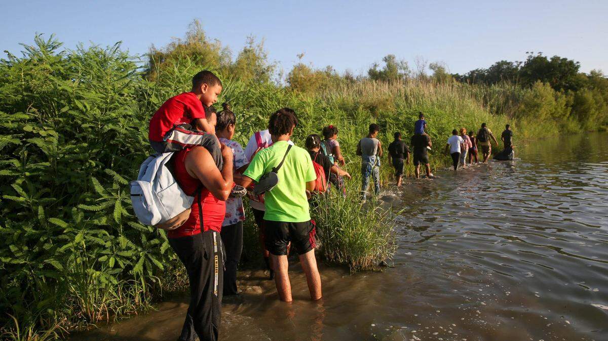 Un grupo de inmigrantes caminan por una pequeña isla en el medio del Río Grande mientras intentan llegar a Eagle Pass, Texas, desde México, el 21 de julio de 2023.
