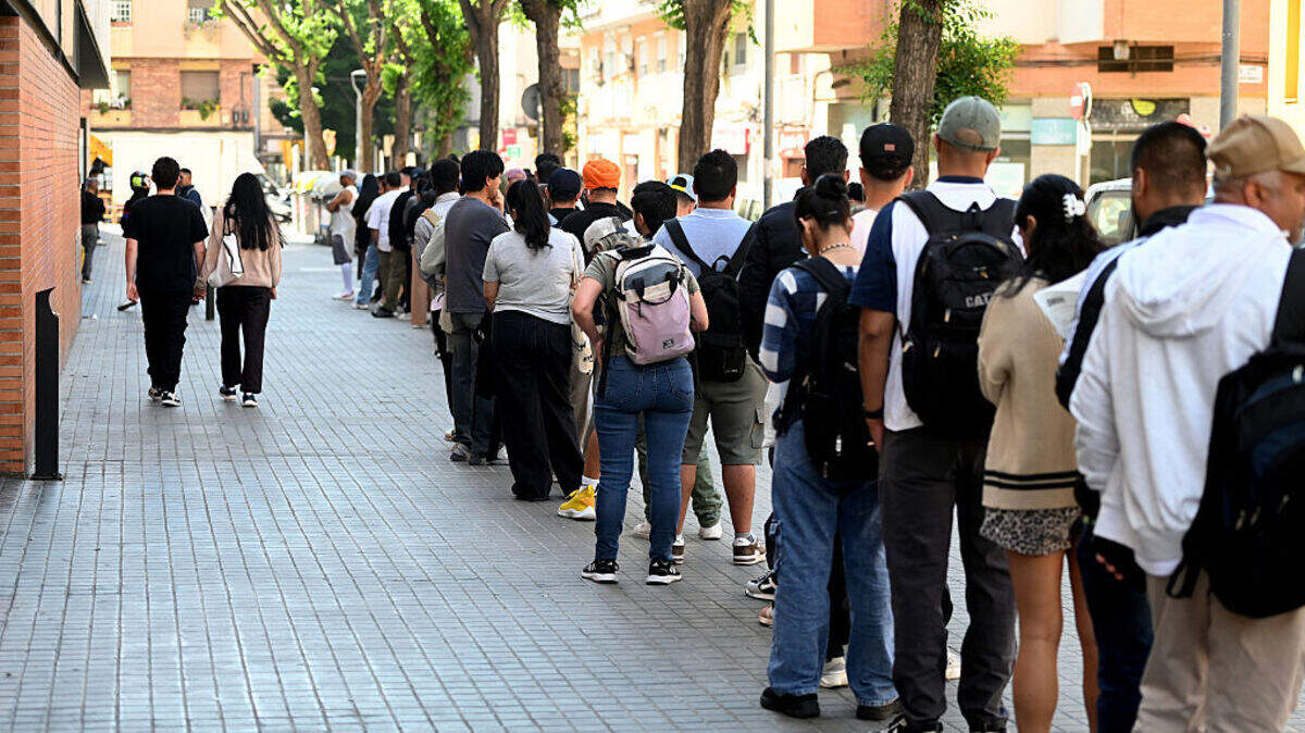 Una larga fila de inmigrantes espera su turno para obtener la documentación oficial en el proceso para regularizar su situación legal en España, el 27 de abril de 2026 en Barcelona.