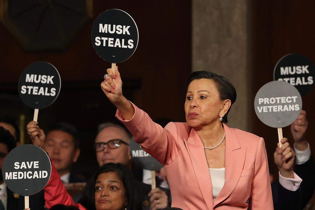 La representante Nydia Velázquez muestra una pancarta junto con otros colegas demócratas durante el discurso del presidente Donald Trump en la sesión conjunta del Congreso, el 4 de marzo de 2025 en Washington, DC. 