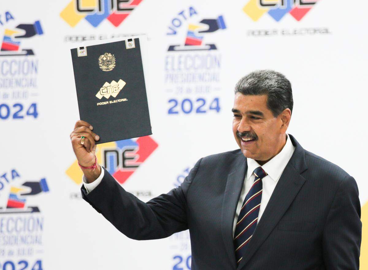 Venezuelan ruler Nicolás Maduro holds up the National Electoral Council document that certified his reelection, on Monday, July 29, 2024, in Caracas.